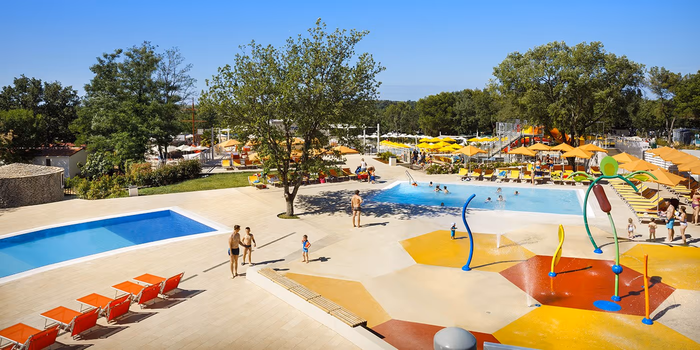 Overzicht van de zwembaden, speelzone en ligbedden in het aquapark van Camping Lanterna