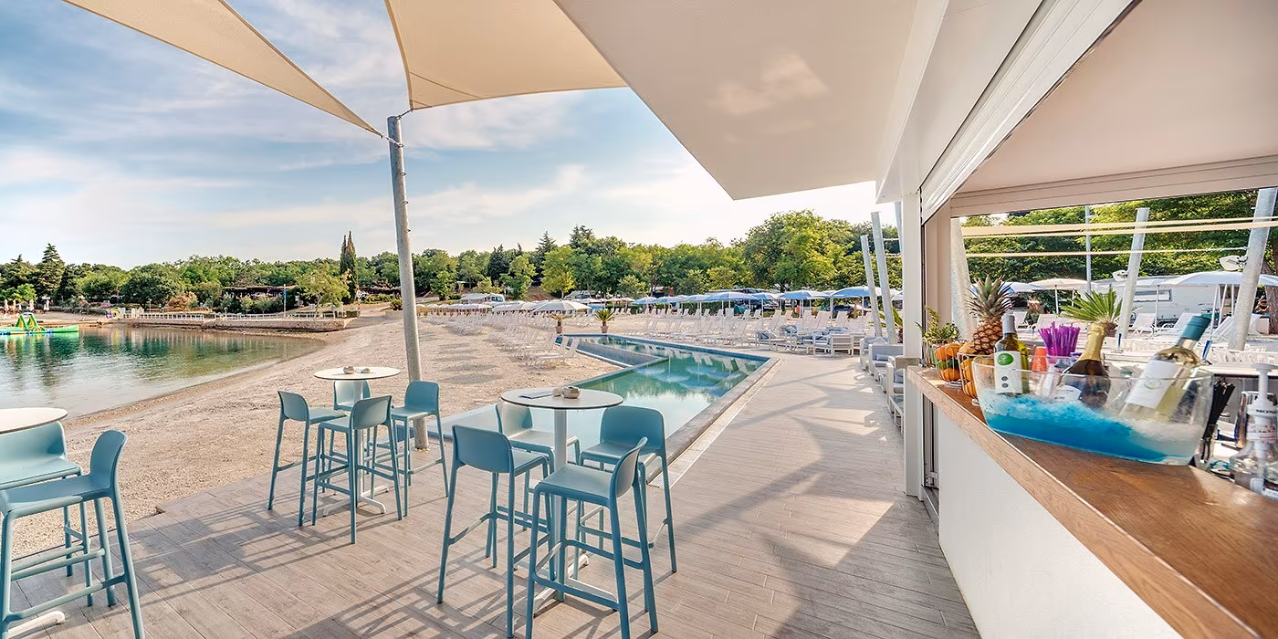 Terras van de Beat Beach Bar met hoge tafels en panoramisch zeezicht op Camping Lanterna