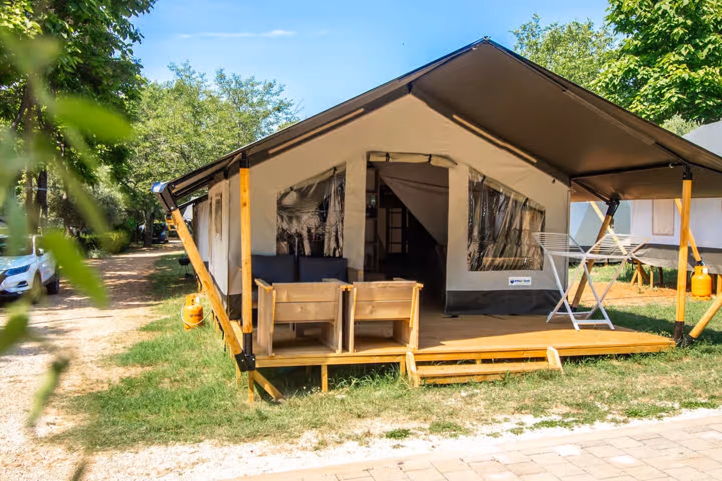Safaritent Comfort op Camping Lanterna met een luifel op houten palen, houten bankjes op het terras en een wasrek ernaast