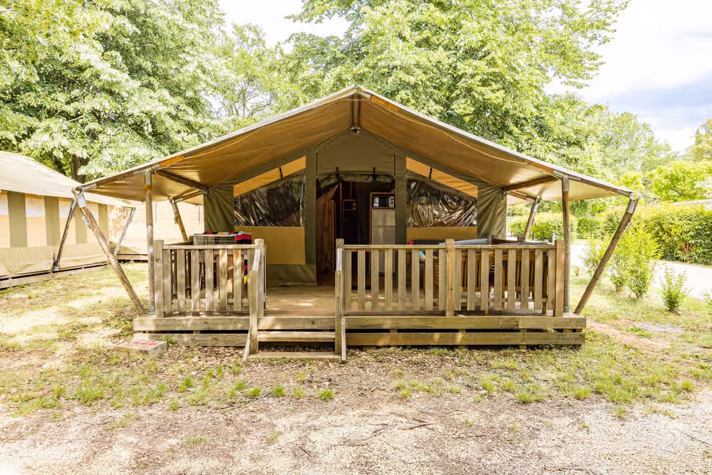 Safaritent Relax op Camping Lanterna met een brede luifel en een omheind houten terras, op een plek met gras en grind