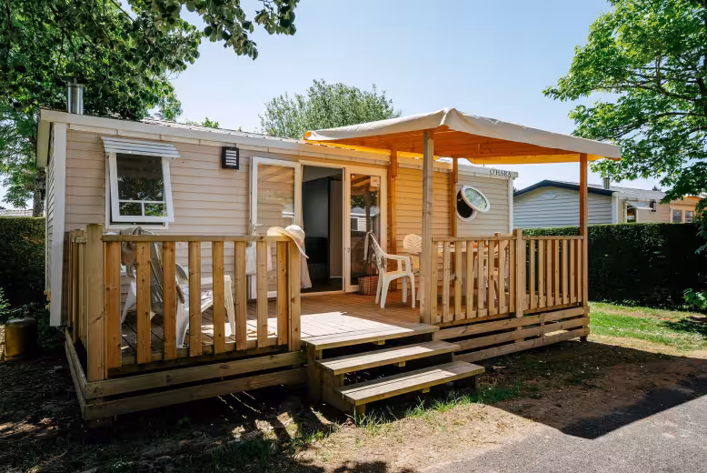 Lichte Comfort-stacaravan van Eurocamp op Camping Lanterna, met een houten terras onder een zonnezeil en tuinstoelen