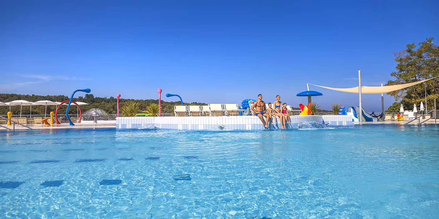 Gezinnen zwemmen en ontspannen in het grote buitenbad van Camping Lanterna