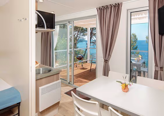 Woonkamer van een Vista Mare-variant met openslaande deuren naar zee, Camping Lanterna