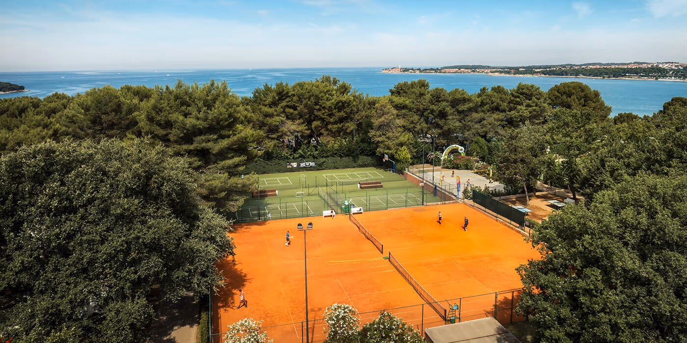 Luchtfoto van de tennisbanen tussen het bos en de Adriatische Zee bij Camping Lanterna