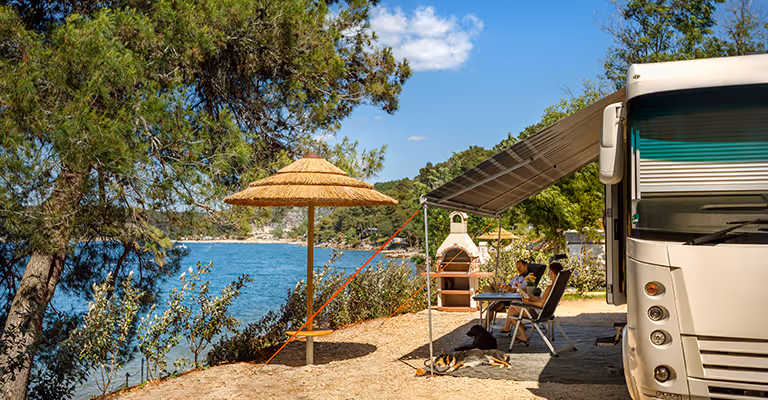 Camper met rieten parasol op een Marbello Luxury Mare plaats aan zee op Camping Lanterna