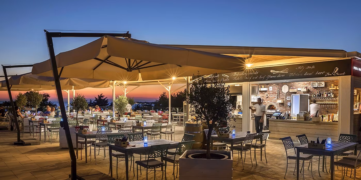 Verlicht terras van restaurant Grano Duro in de avond op Camping Lanterna