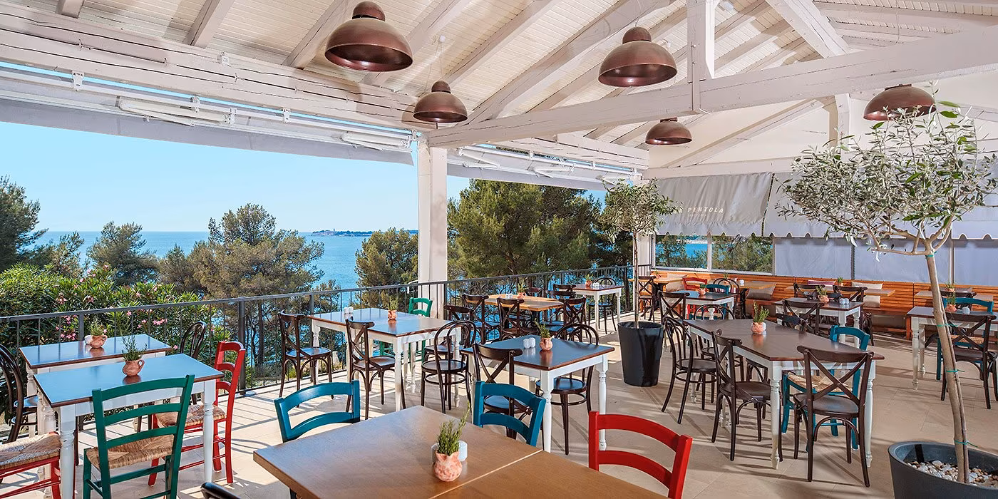 Kleurrijk terras van trattoria La Pentola met uitzicht op zee, Camping Lanterna