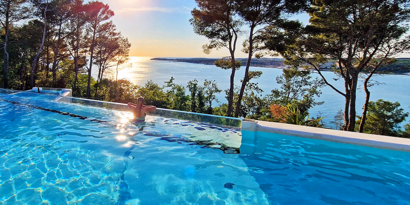 Zwemmer in het Punto Blu-zwembad met zee en avondzon op Camping Lanterna