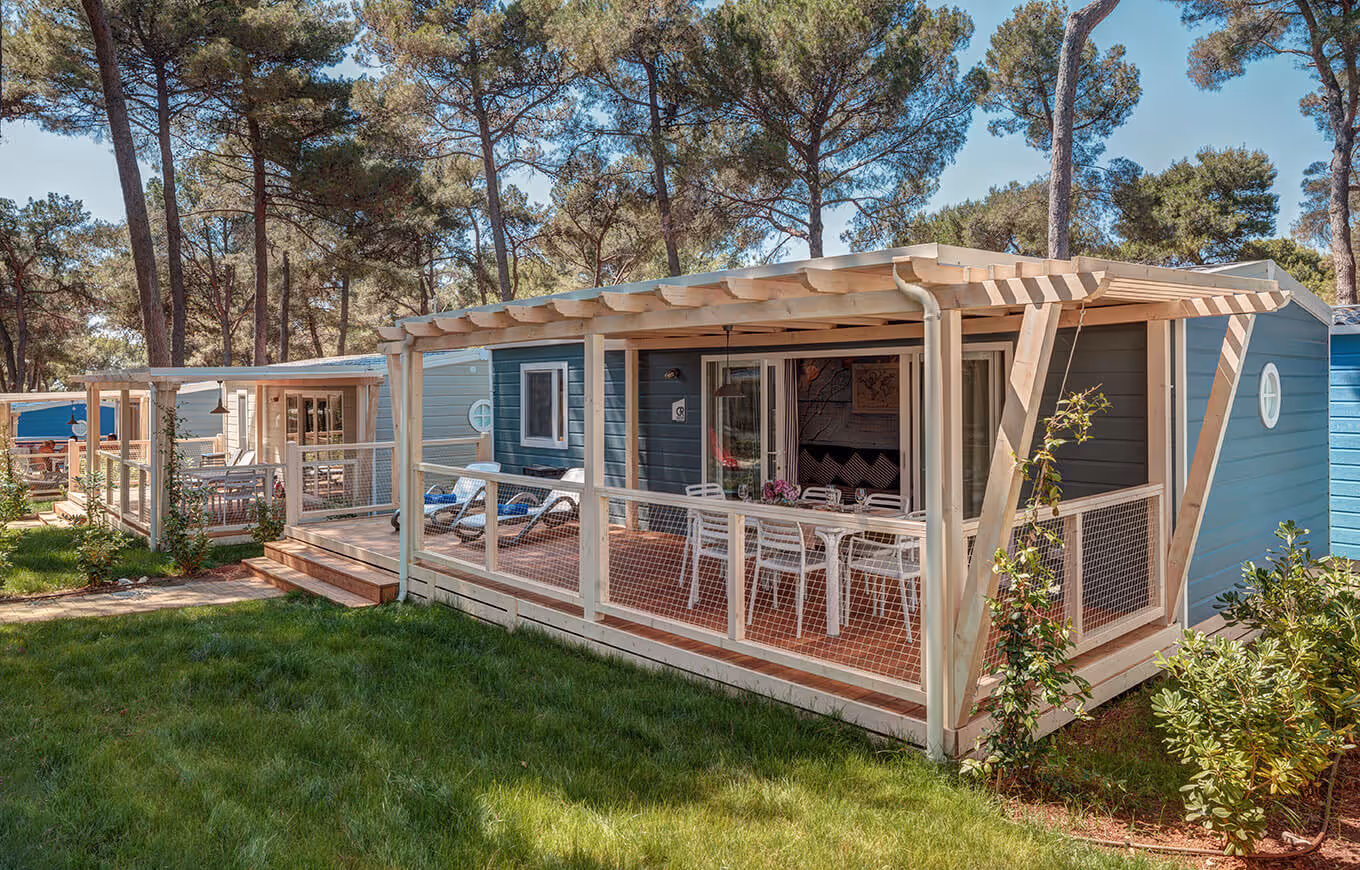 Blauwe Marine Home met pergola en terras onder de parasoldennen op Camping Lanterna