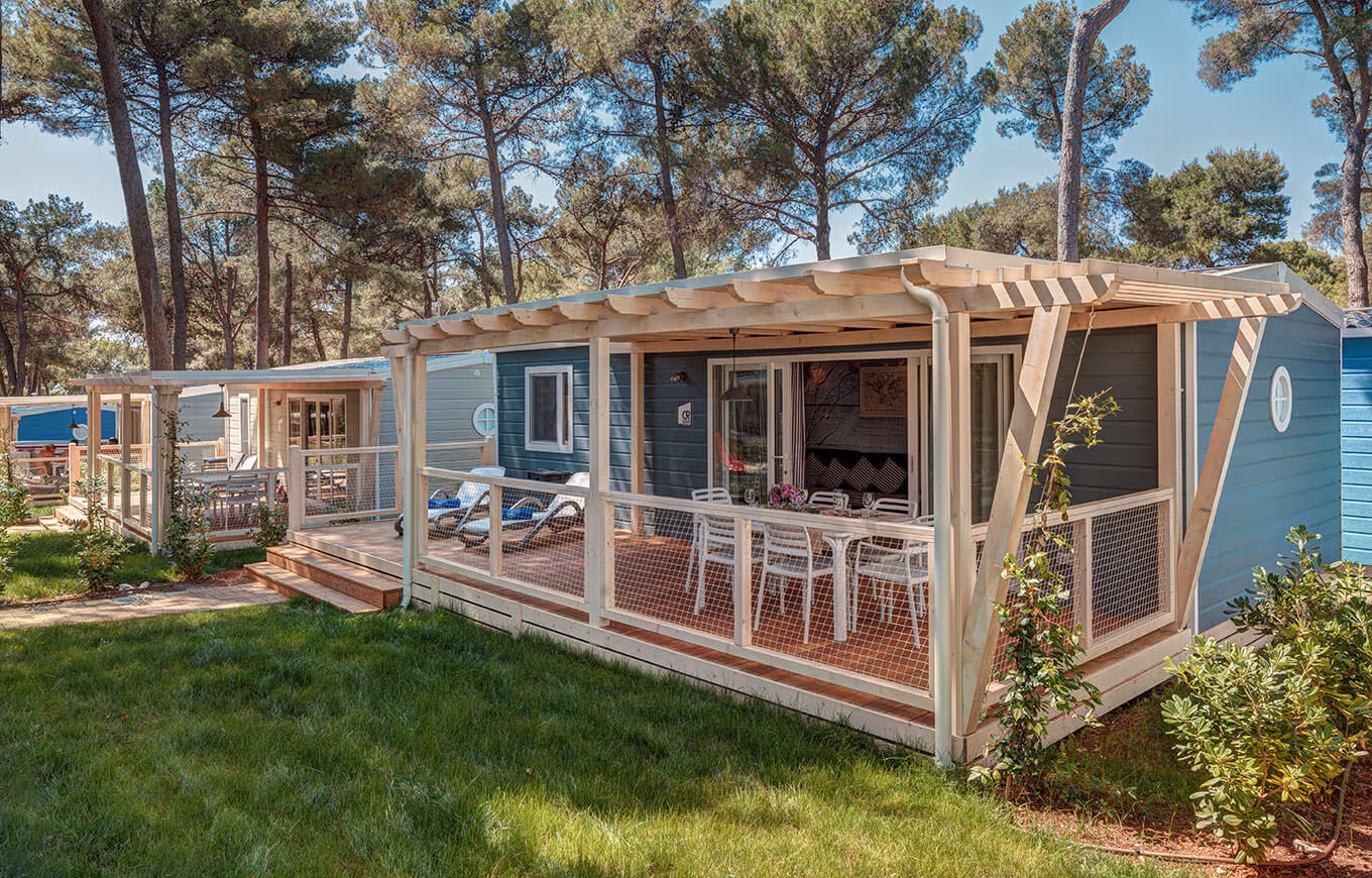 Blauwe Marine Home met pergola en terras onder de parasoldennen op Camping Lanterna