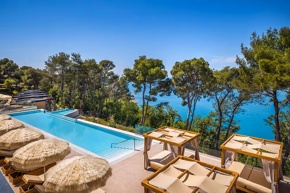 Infinityzwembad met rieten parasols en loungecabanas boven zee in Punto Blu, Camping Lanterna